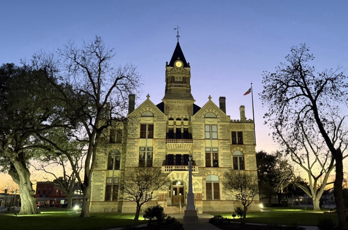Floodlit stone courthouse with a clock tower against a deep blue evening sky